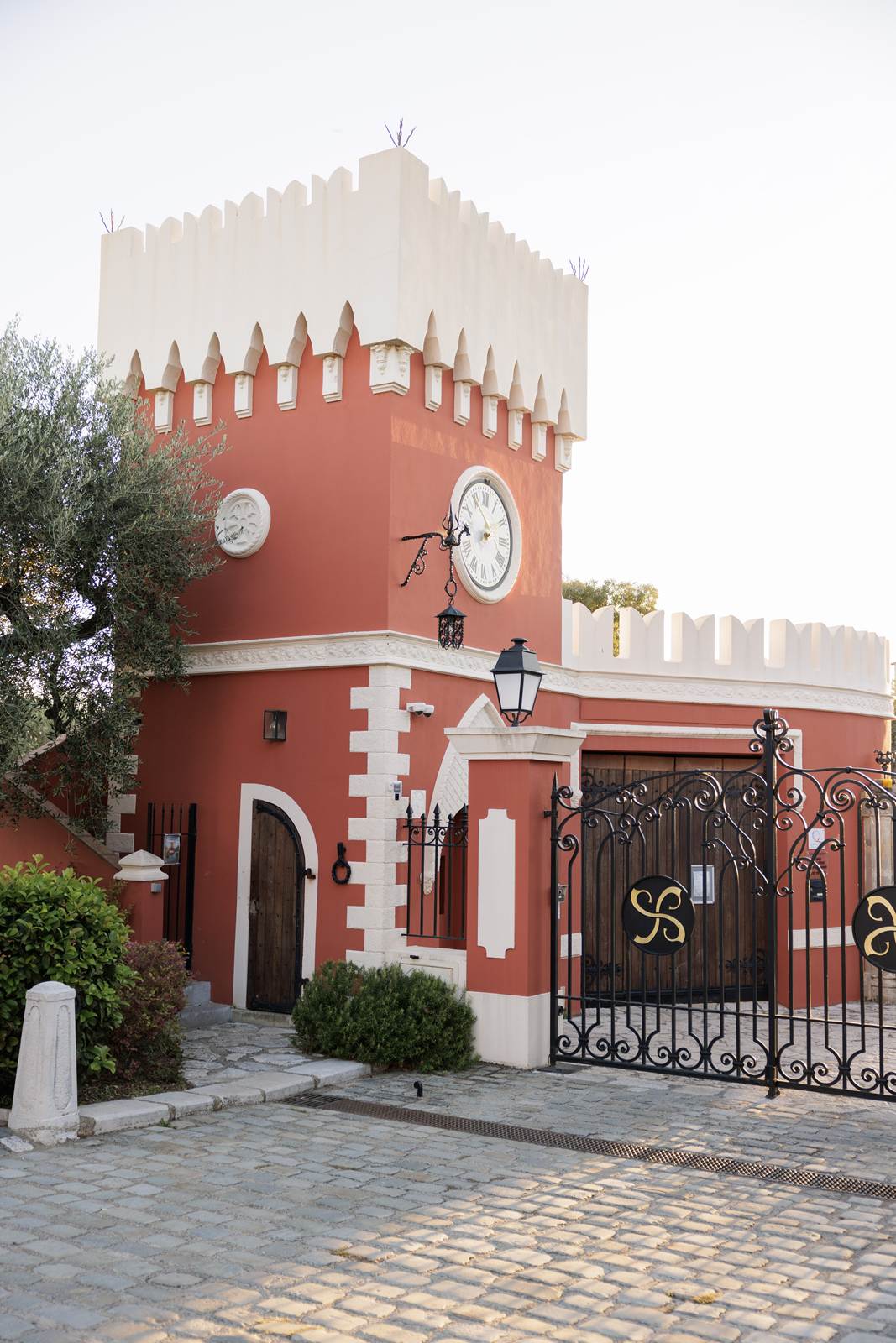The clock tower and gates of a château, in the evening sun