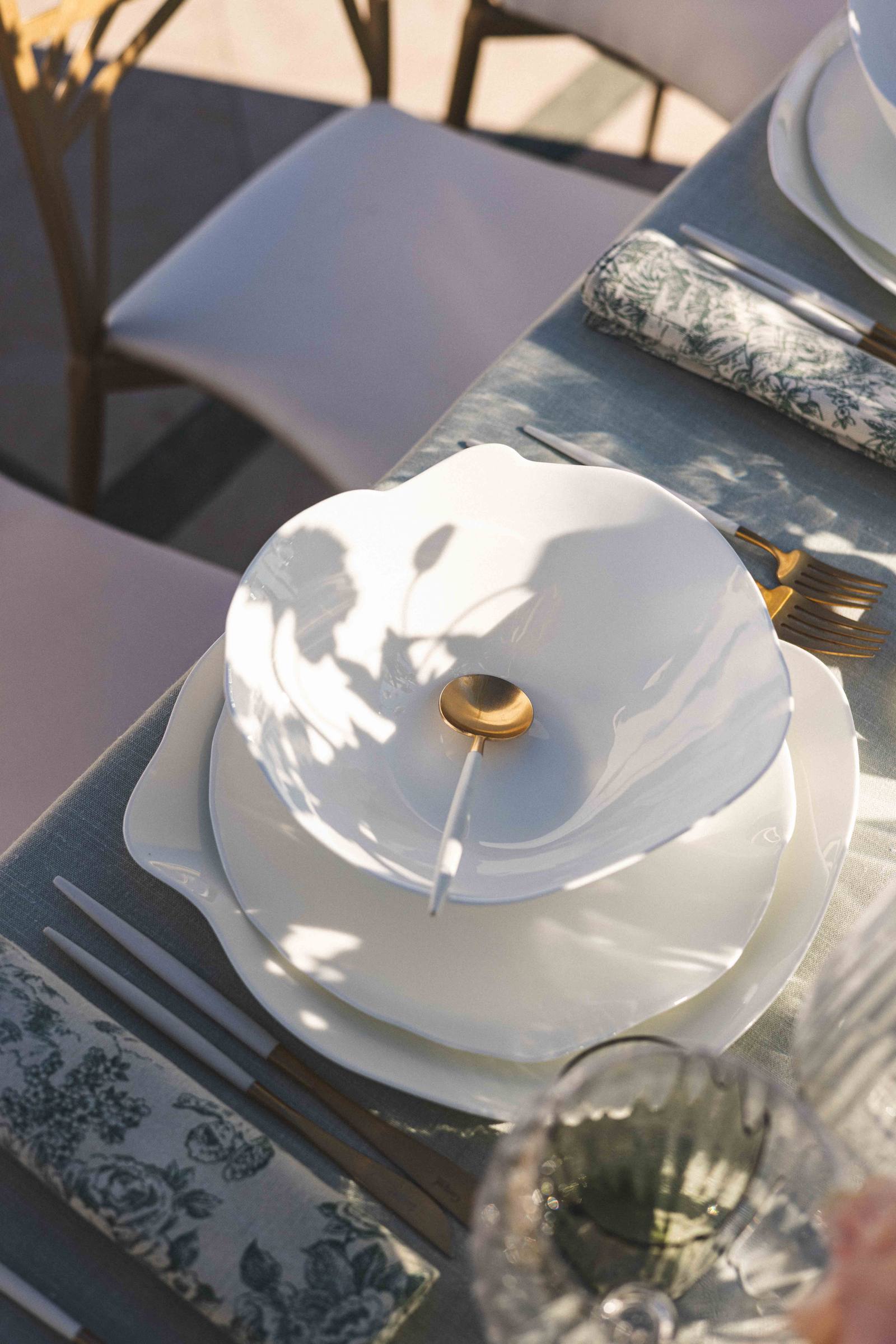 A white plate and its gold spoon, seen from above