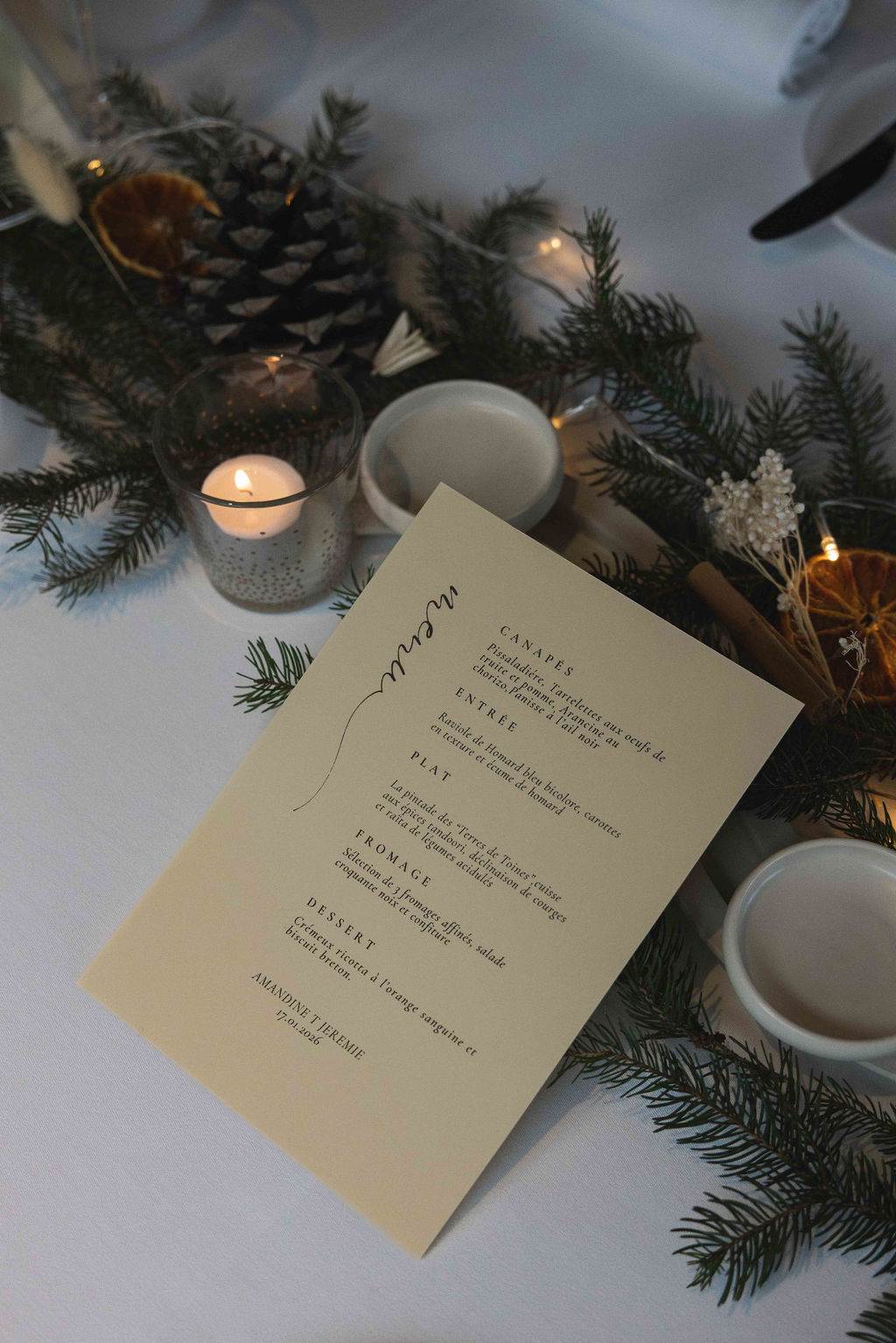 The dinner menu on the table, among fir branches and candles