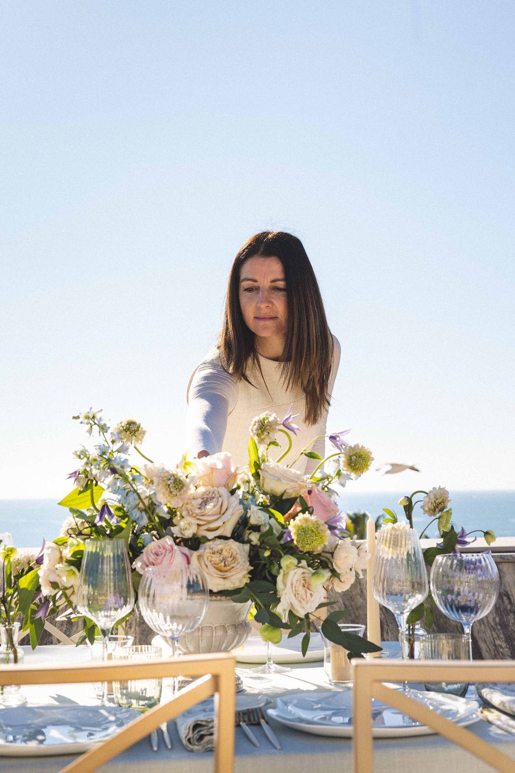 Jennifer Taddei arranging a floral centrepiece above the sea