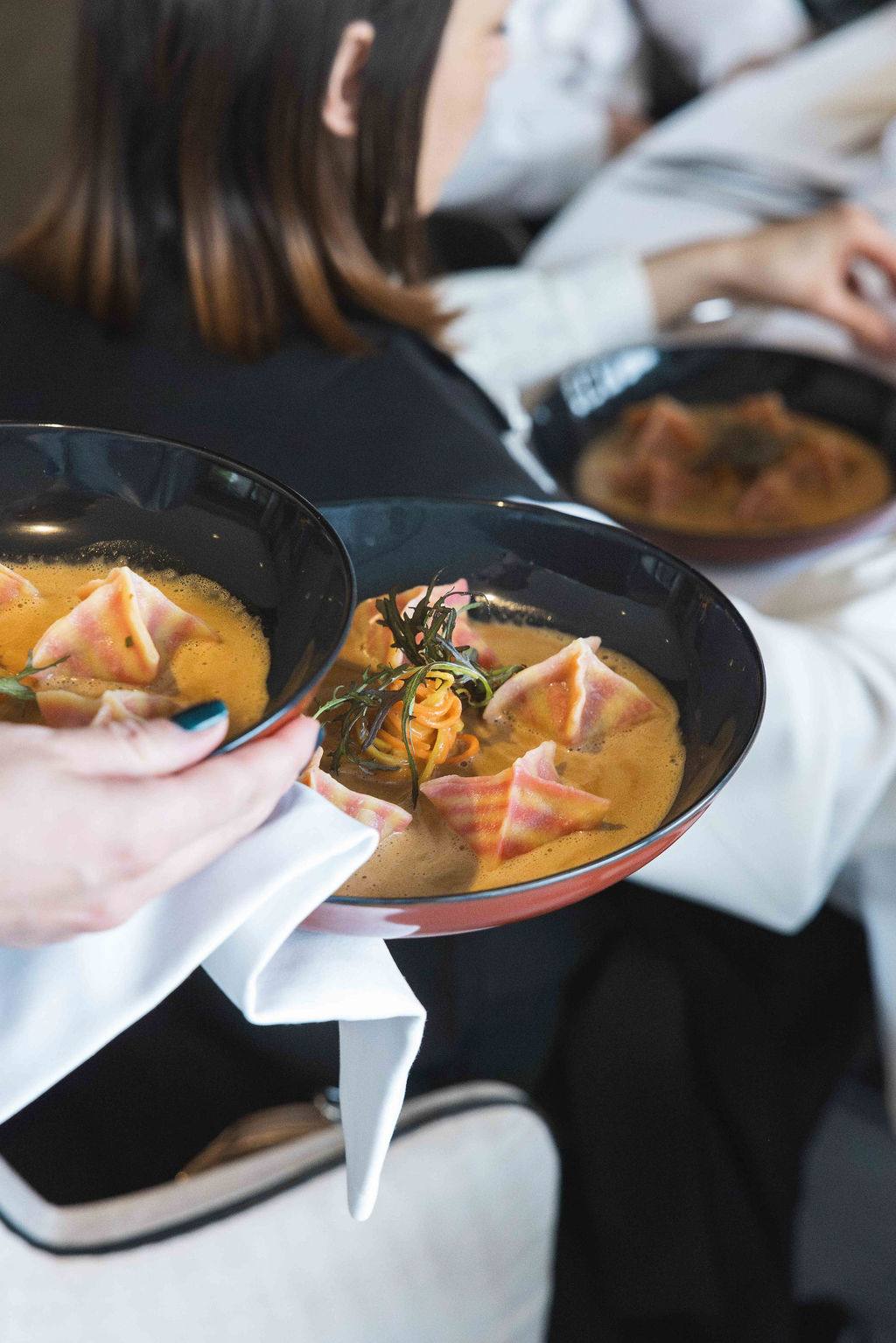 Ravioli in a shellfish sauce, plated and carried to the table