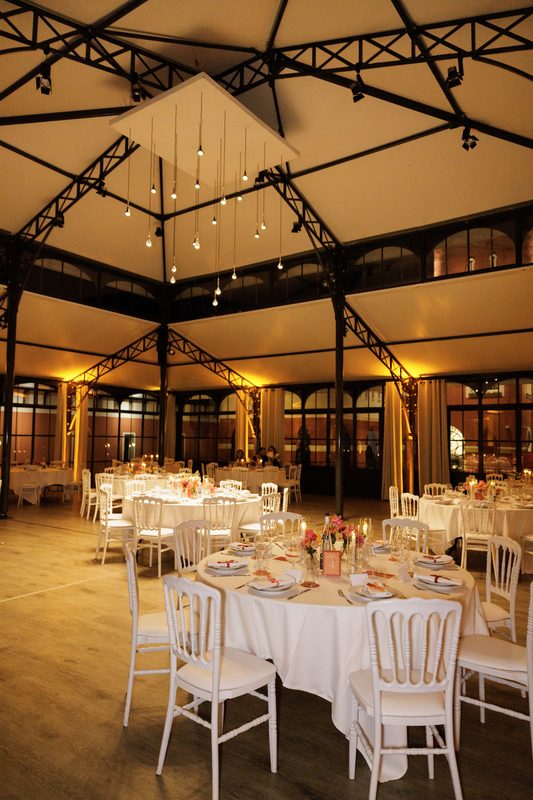 A large hall laid with round tables under a lit glass roof