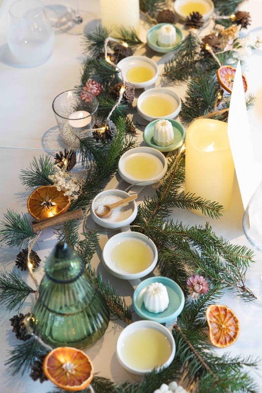 A winter table laid with candles, pine branches and small bowls