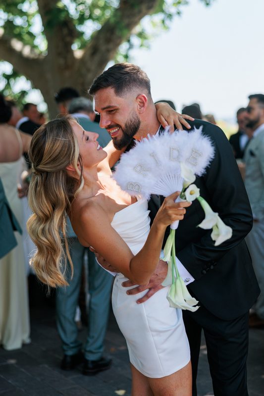 A bride and groom embracing among their guests